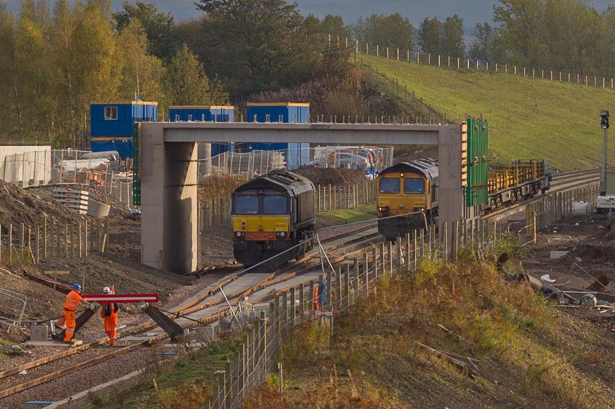 Access to the Borders Railway is currently guarded by a temporary barrier, seen here in the process of being raised to allow the exit of the GB Railfreight 66706 Nene Valley with the track laying train at the end of the day’s activities. Waiting on the adjacent track is Direct Rail Serices 66302, ready to attach itself to the rear of the train before advancing then reversing to Millerhill for the night on October 8