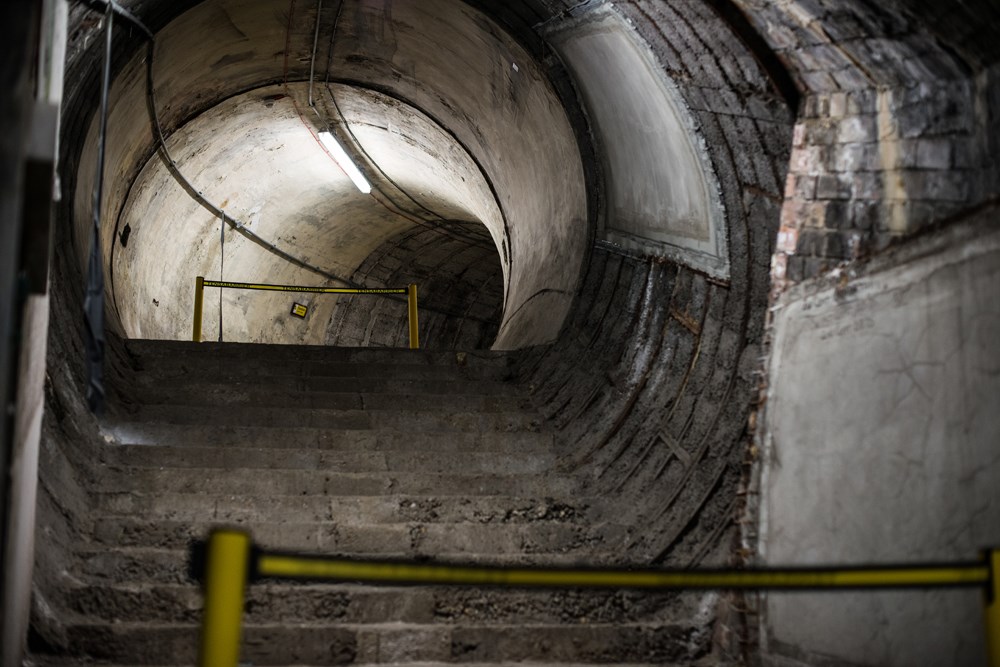 At Aldwych, looking up the crumbling staircase behind the door off Platform 2, next to its overrun tunnel. The top of the staircase leads to a passageway that curves round to a crossroads of more passageways. They were never in public use, as evidenced from the lack of tiling on the walls.