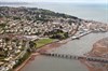 A First Great Western High Speed Train threads its way through the coastal town of Teignmouth, and is about to pass under Shaldon Bridge, which links the town with the village of Shaldon, located on the other side of the River Teign. Teignmouth was the last place to be invaded by a foreign power, when the French landed in 1690. Previously a fishing port, it became a fashionable resort during Georgian times. It is home to a port, and in this image the barge that is now at work repairing the sea wall at Dawlish is being prepared in the docks. First Great Western train at Shaldon Bridge