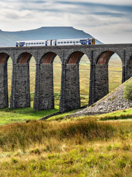 Train crossing the Ribblehead Viaduct with Ingleborough beyond Yorkshire Dales National Park England. ALAMY